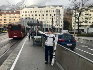 Sara steht mit Ski bei der Bushaltestelle