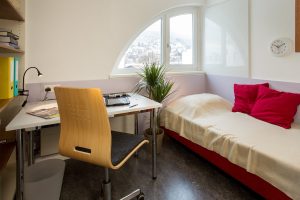 Einzelzimmer mit Bett und Schreibtisch