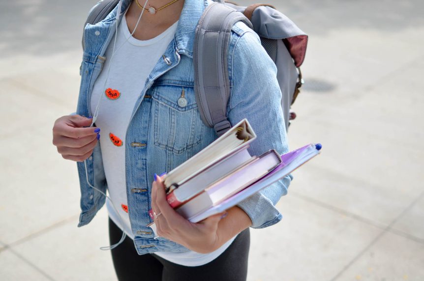 Frau mit Rucksack und Notizbüchern in der Hand