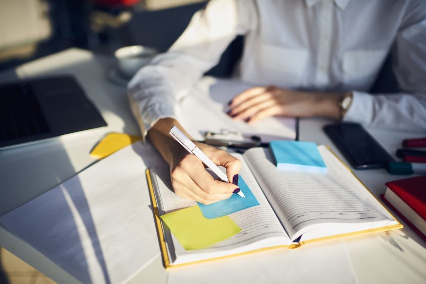 Studentin schreibt in ihren Lernplan auf Post-it