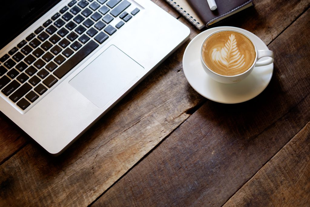 Laptop und Cappuccino auf einem Holztisch