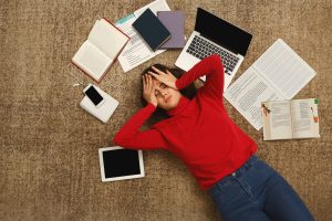 Studentin liegt mit gestresstem Blick am Boden