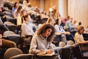 Studentin sitzt im Vorlesungssaal und macht sich Notizen