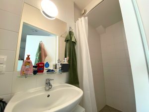 Badezimmer mit Dusche mit weißem Duschvorhang