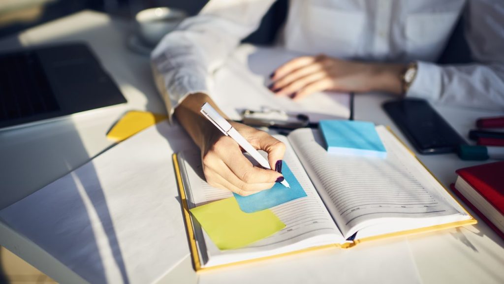 Studentin schreibt in ihren Lernplan auf Post-it