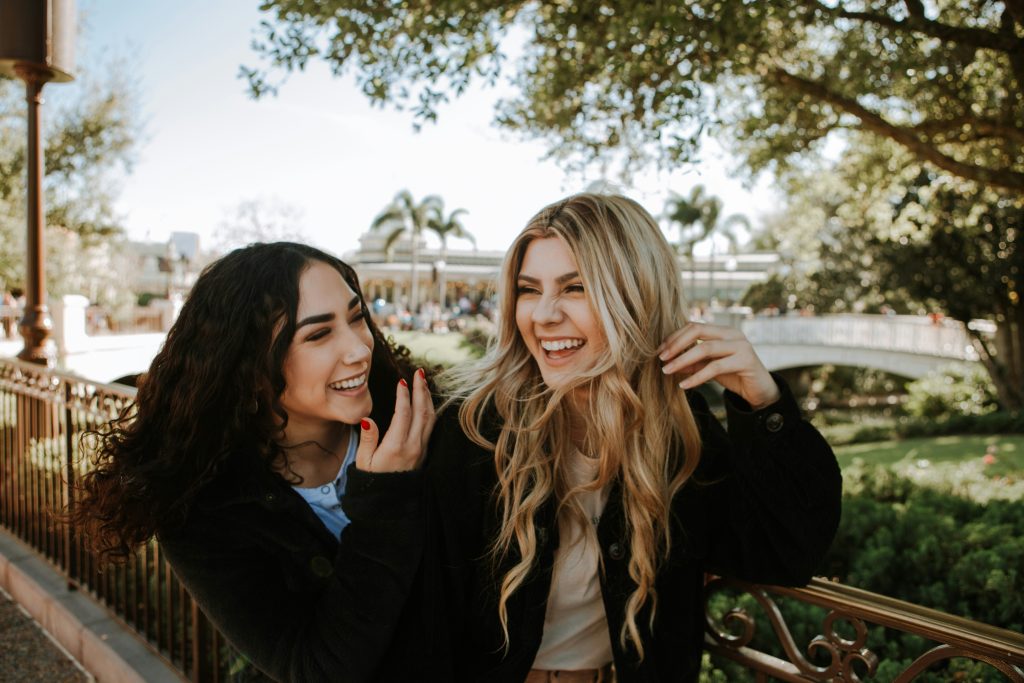 Zwei junge Frauen lachen gemeinsam in einem Park