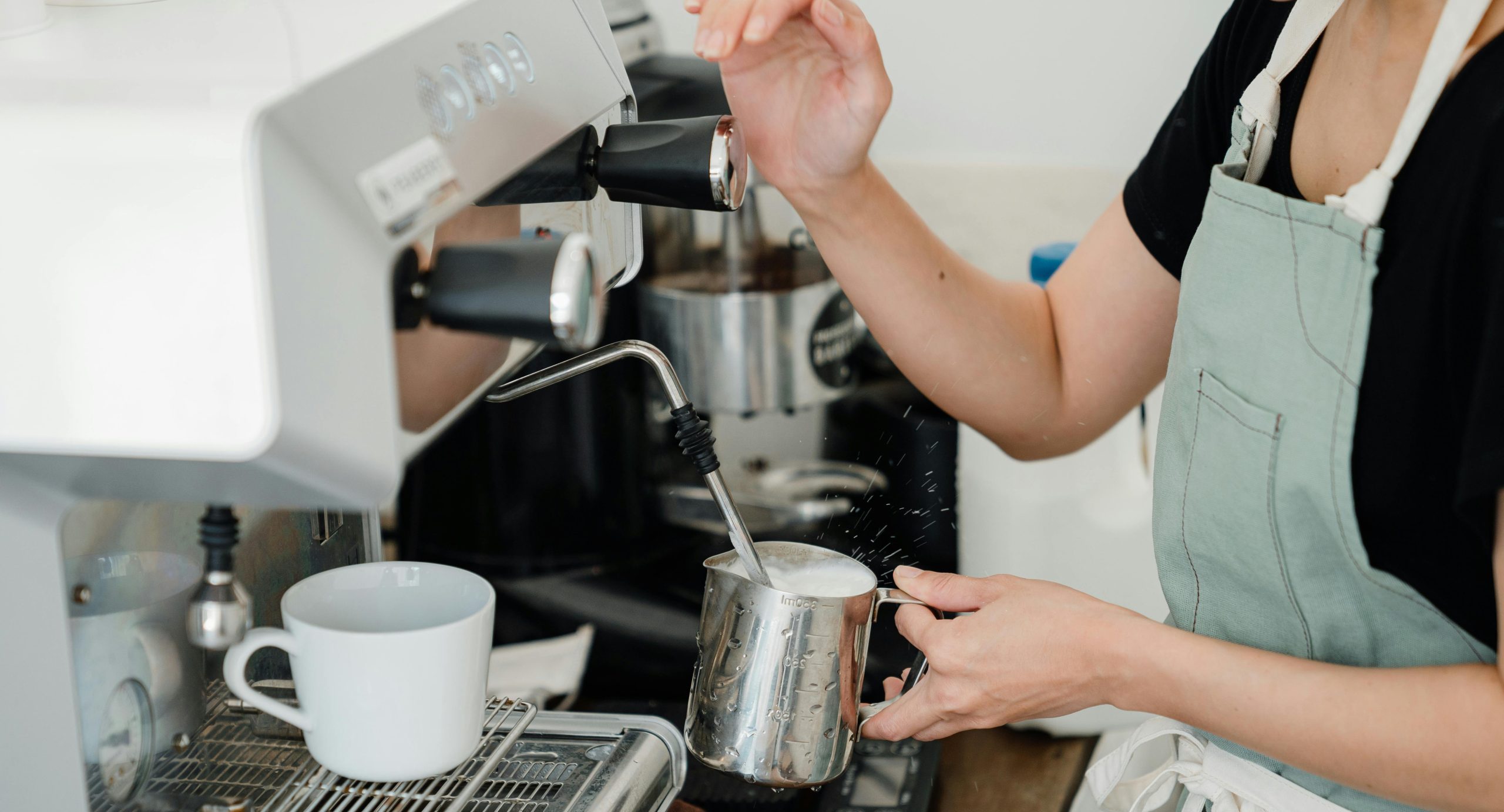Barister schäumt Milch an Kaffeemaschine auf